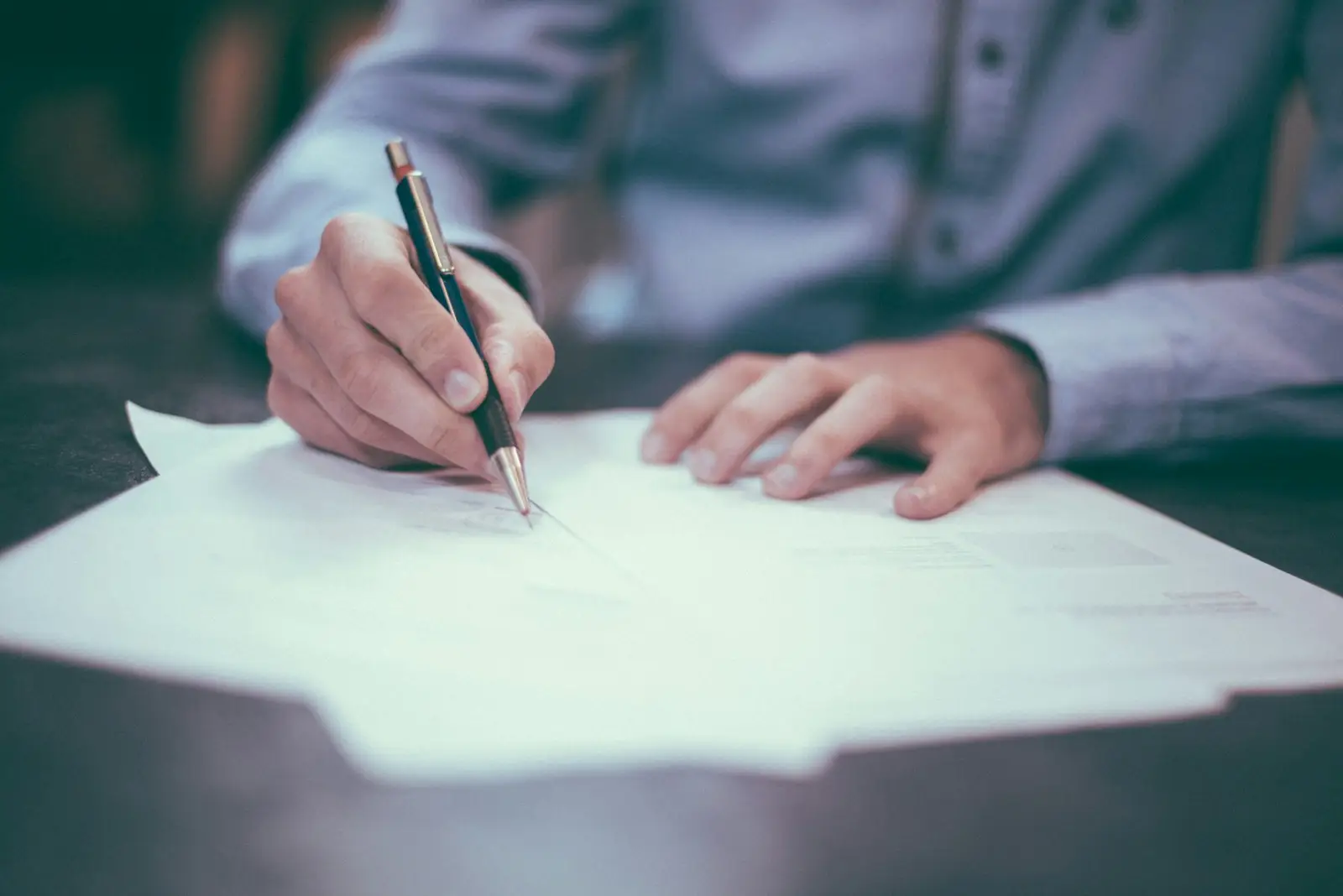 A person signing a legal document at a desk